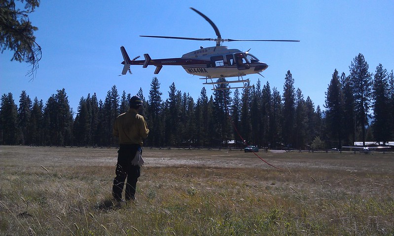 Helicopter hovering over the ground in the distance; person in the foreground