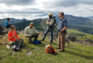 Five people on top of a mountain having a conversation