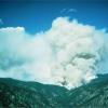 Smoke billowing into the sky from a mountainous landscape